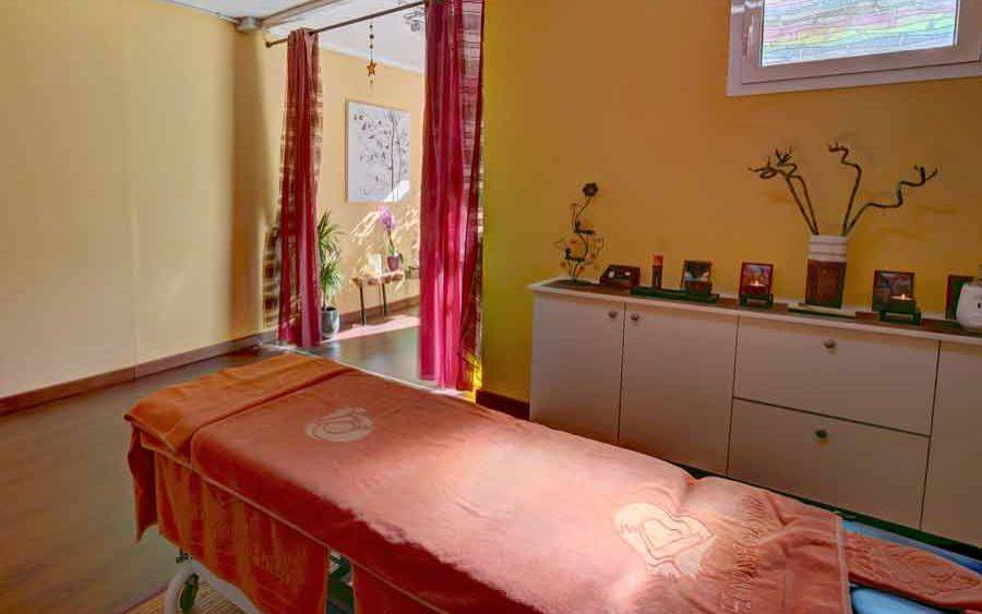 Massageraum im SBH Monica Beach Resort mit gelben Wänden, rotem Vorhang und Massagetisch.