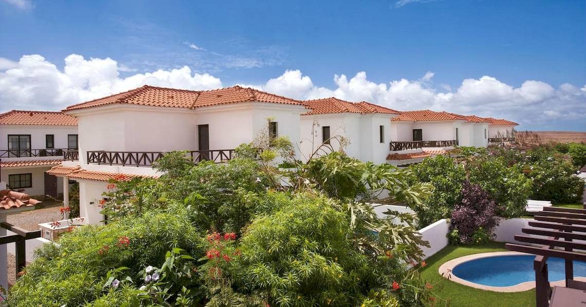 Aussenansicht des Melia Tortuga Beach Hotels mit weissen Villen, roten Dächern und umliegenden Pflanzen.