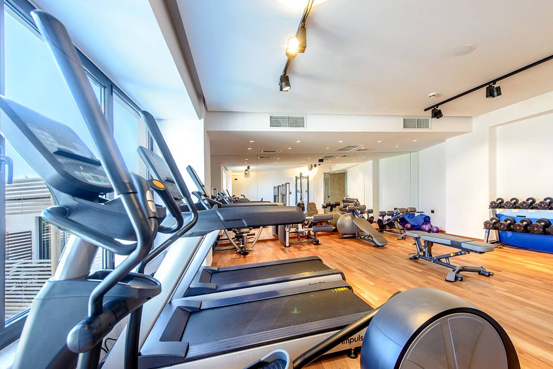 Fitnessraum im Stella Island Luxury Resort & Spa mit mehreren Laufbändern und Hanteln.