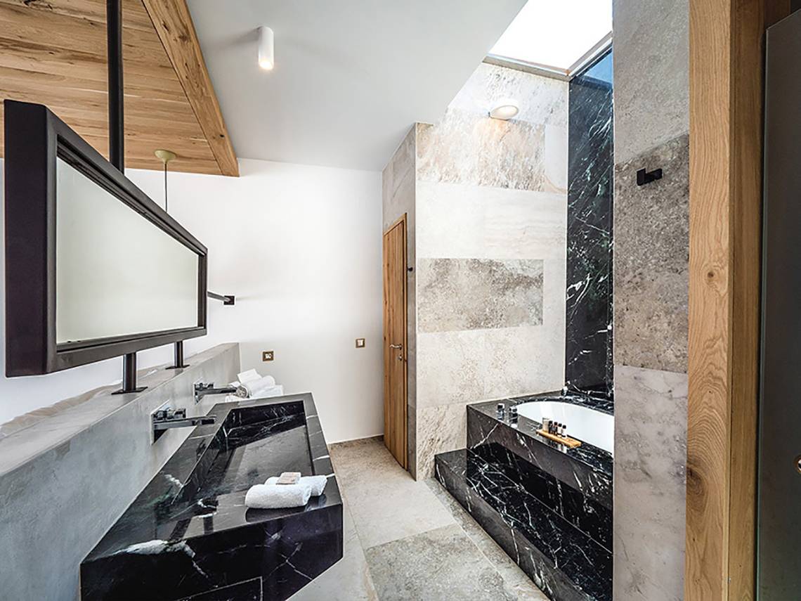 Badezimmer des Stella Island Luxury Resort & Spa mit schwarzem Marmor und Badewanne
