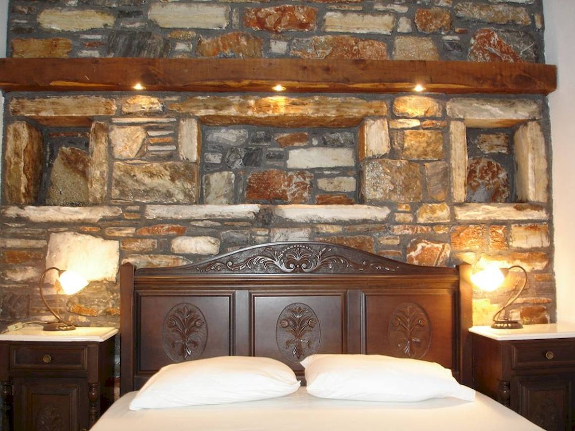 Schlafzimmer in der Villa Romantica mit Steinwand, betten und Nachttischen.
