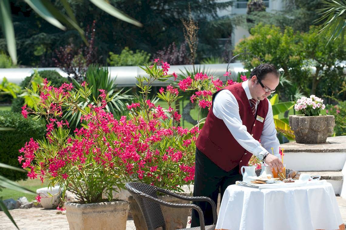 Ein Kellner serviert ein Frühstück im Garten des Sierra Silvana Hotels.