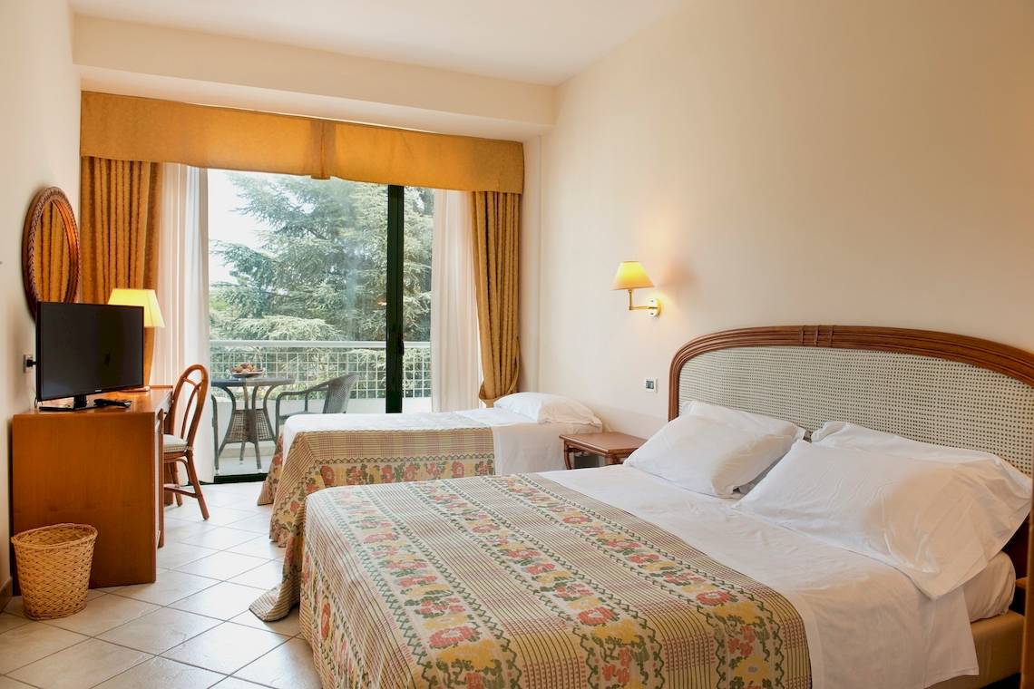 Zimmer im Sierra Silvana Hotel mit zwei Betten, Fernseher und Balkon.