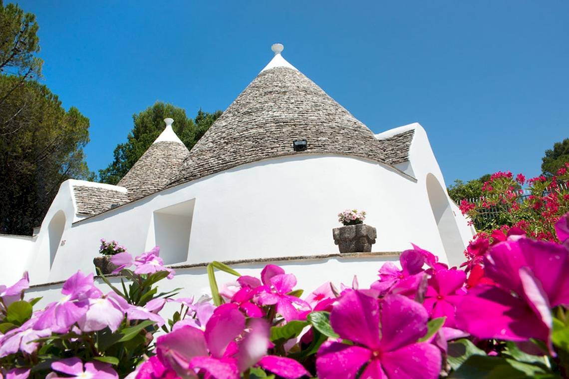 Außenansicht des Sierra Silvana Hotels mit pinken Blumen im Vorgarten.