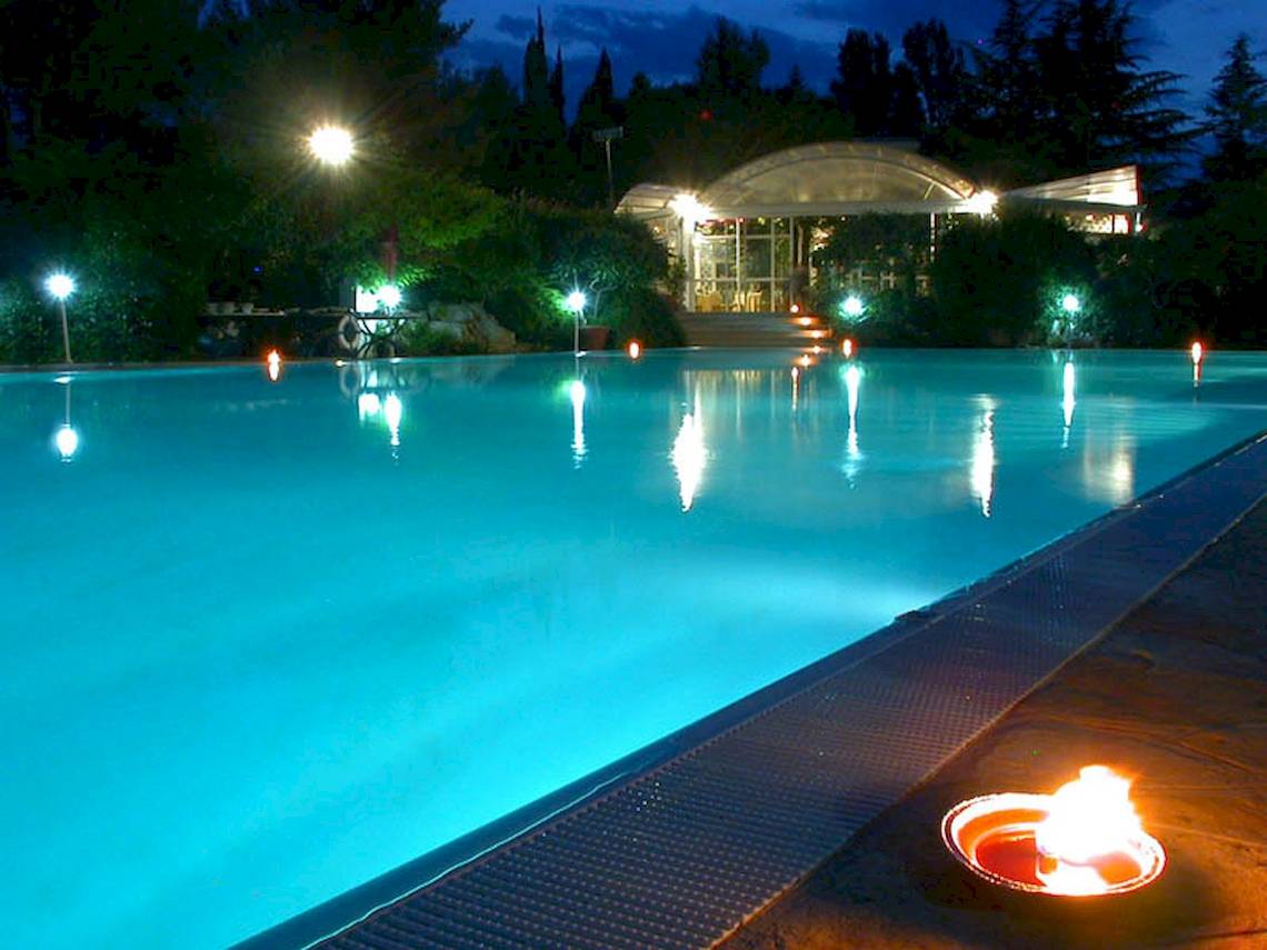 Ein Pool bei Sierra Silvana Hotel in der Nacht mit blauem Wasser und Lichtern.