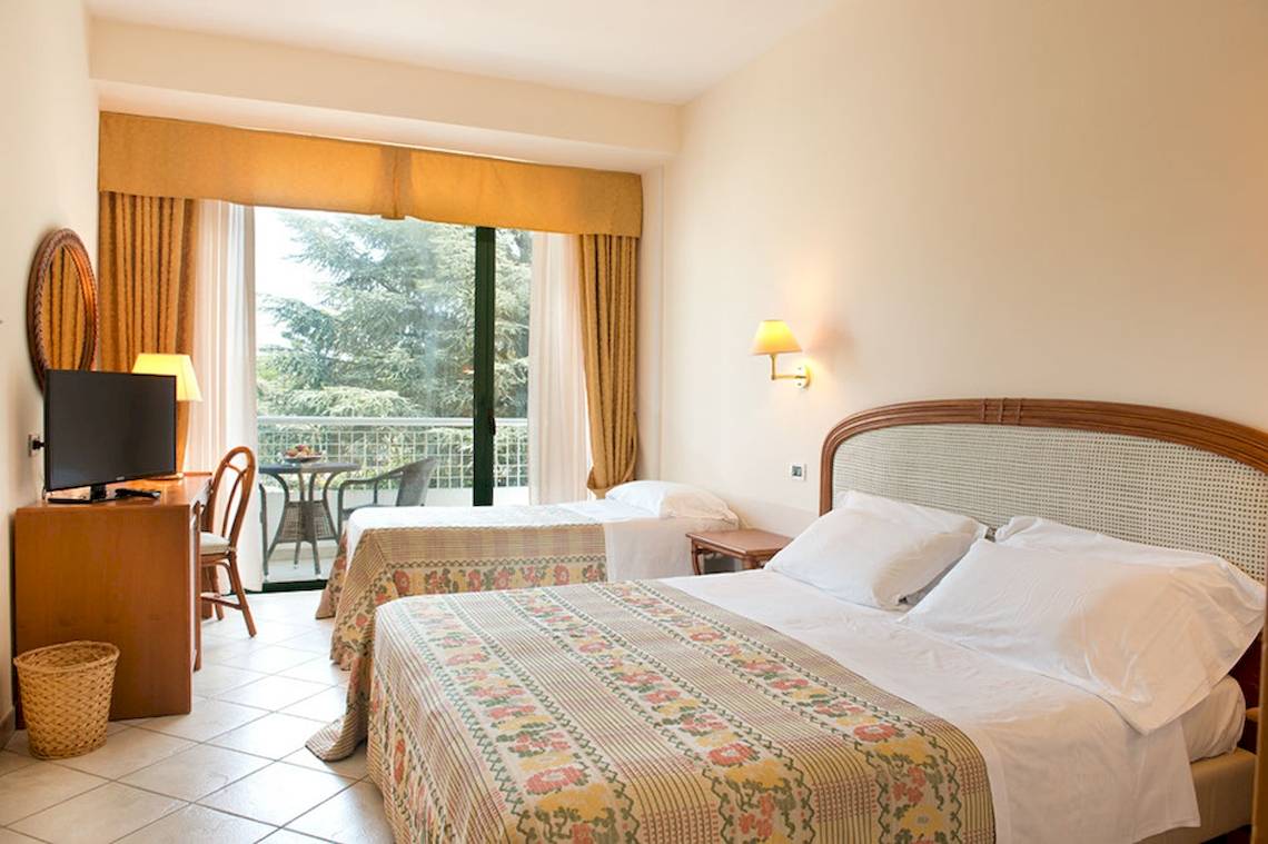 Doppelzimmer im Sierra Silvana Hotel mit zwei Betten, Fernseher, Schreibtisch und Balkon.