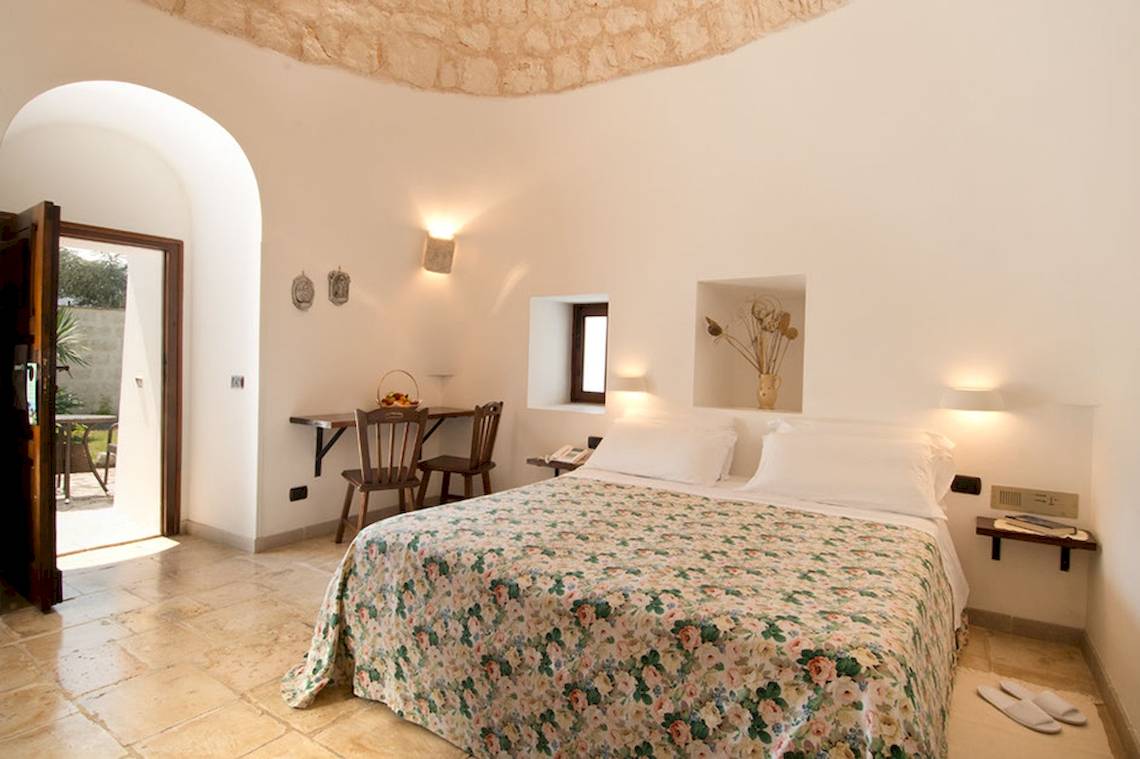 Innenansicht eines Schlafzimmers im Hotel Sierra Silvana mit Bett, Tisch und offenem Tür