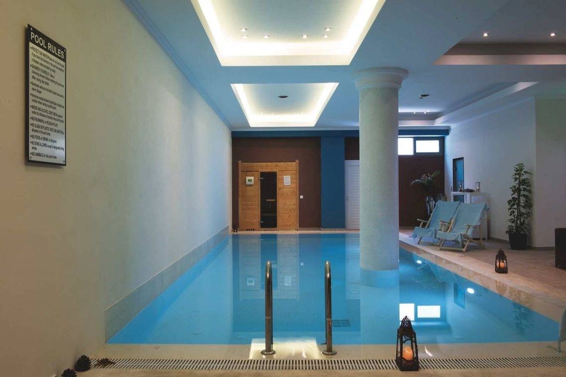 Innenpool im Alkyna Lifestyle Beach Resort mit weißen Wänden, blauem Wasser und Lounge-Bereich.