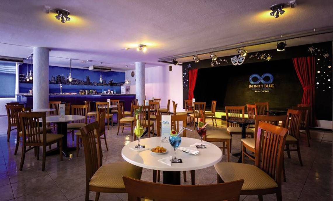 Innenbereich des Bahia Flamingo Hotels mit gepolsterten Stühlen, Tischen und einer Bar im Hintergrund.