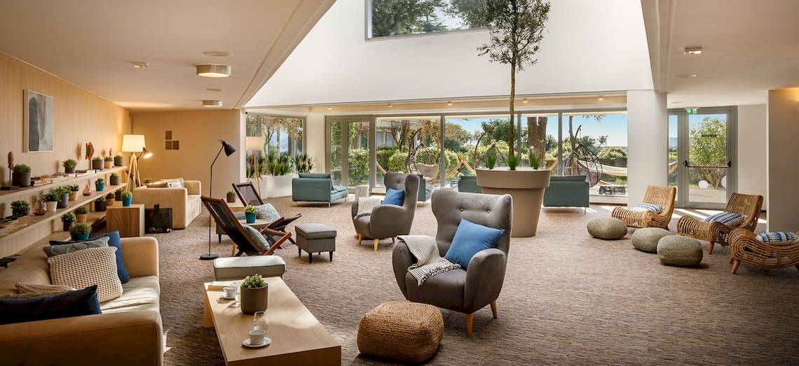 Hotellobby des Valamar Argosy Hotels mit Möbeln, Pflanzen und Aussicht auf das Meer.