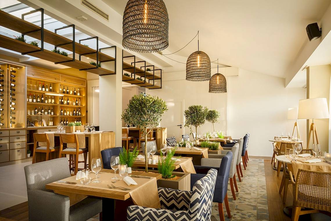 Innenansicht des Restaurants im Valamar Argosy Hotel mit Tischdecken, Weinflaschen und Pflanzen.