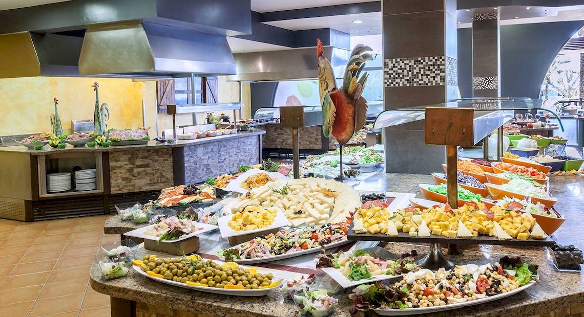 Buffetbereich im Occidental Jandia Playa Hotel mit verschiedenen Speisen und Salaten auf Marmortischen.
