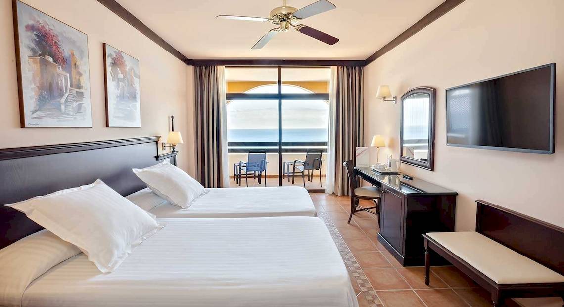 Doppelzimmer im Occidental Jandia Playa Hotel mit Meerblick, zwei Betten, Schreibtisch und Fernseher.