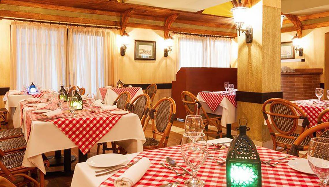 Innenansicht eines Restaurants im Jaz Lamaya Resort mit rot-weiß karierten Tischdecken.