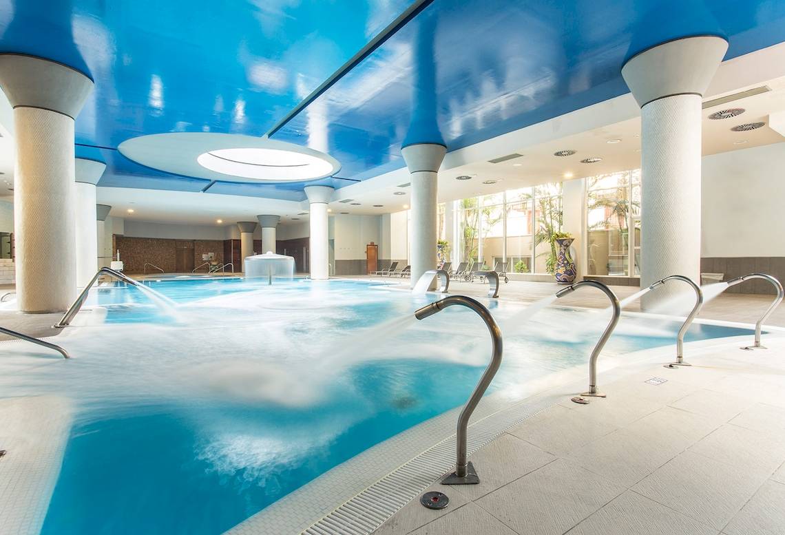 Innenpool des Landmar Costa Los Gigantes Hotels mit blauer Decke und Wasserstrahlen.