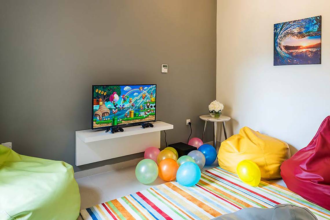 Kinderzimmer mit Fernseher und bunten Ballons auf einem bunten Teppich.