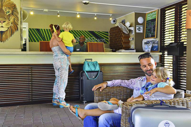 Familie am Empfang des LionsDive Beach Resorts, ein Mann und eine Frau mit zwei Kindern.