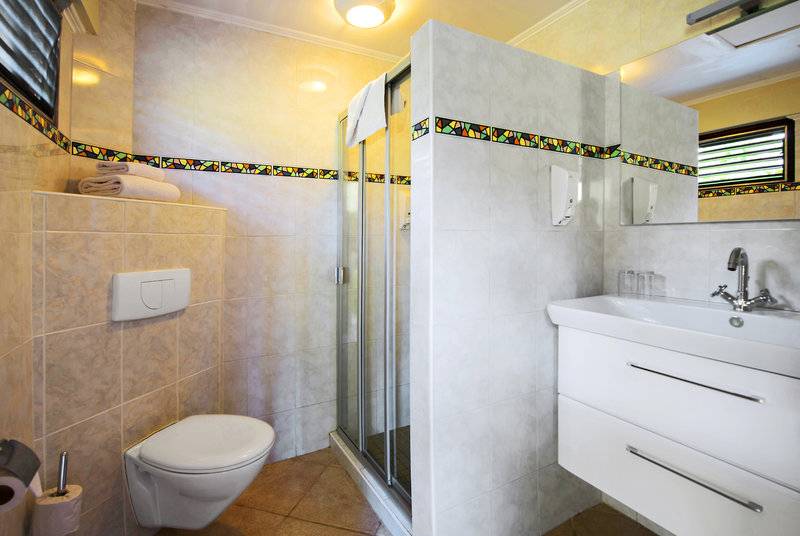 Badezimmer im LionsDive Beach Resort mit Dusche, Toilette und Waschbecken.