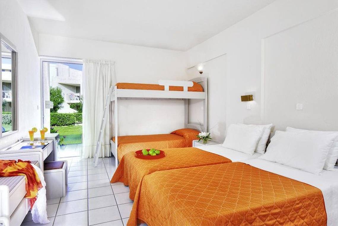 Schlafzimmer im Giannoulis Santa Marina Beach Hotel mit zwei Etagenbetten, einem Schreibtisch und einem Gartenblick.
