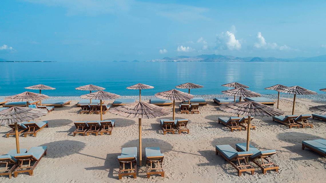 Strandszene mit Liegen und Strohschirmen am Mitsis Ramira Beach Hotel