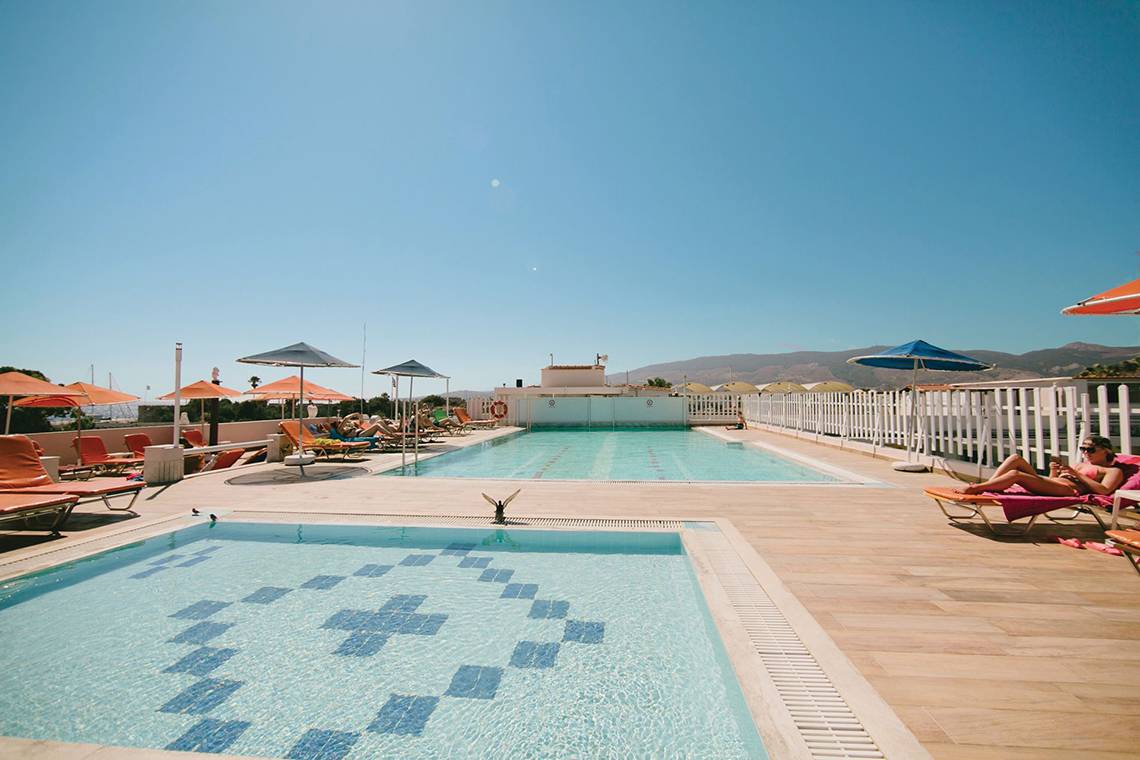 Außenpools des Kosta Palace City Hotel mit Sonnenliegen und Sonnenschirmen.