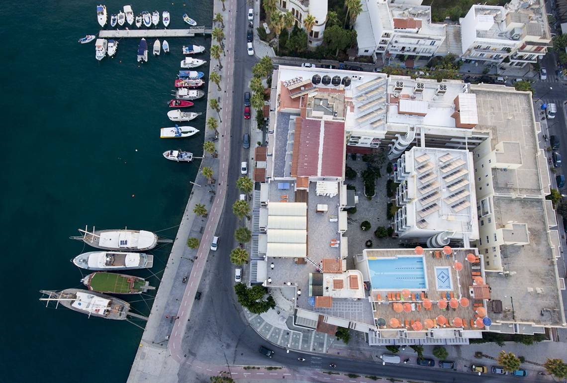 Luftaufnahme des Kosta Palace City Hotel mit Blick auf den Hafen und die umliegenden Gebäude.