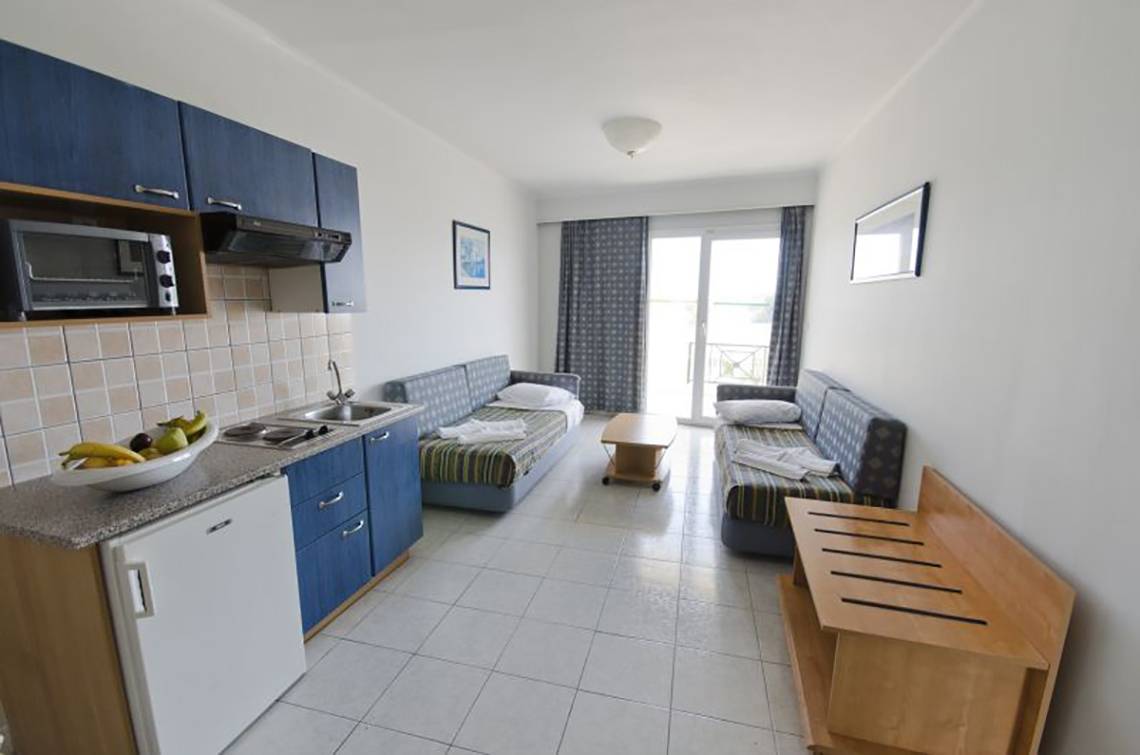 Innenansicht eines Zimmers im Kosta Palace City Hotel mit Küchenbereich und Schlafsofas.