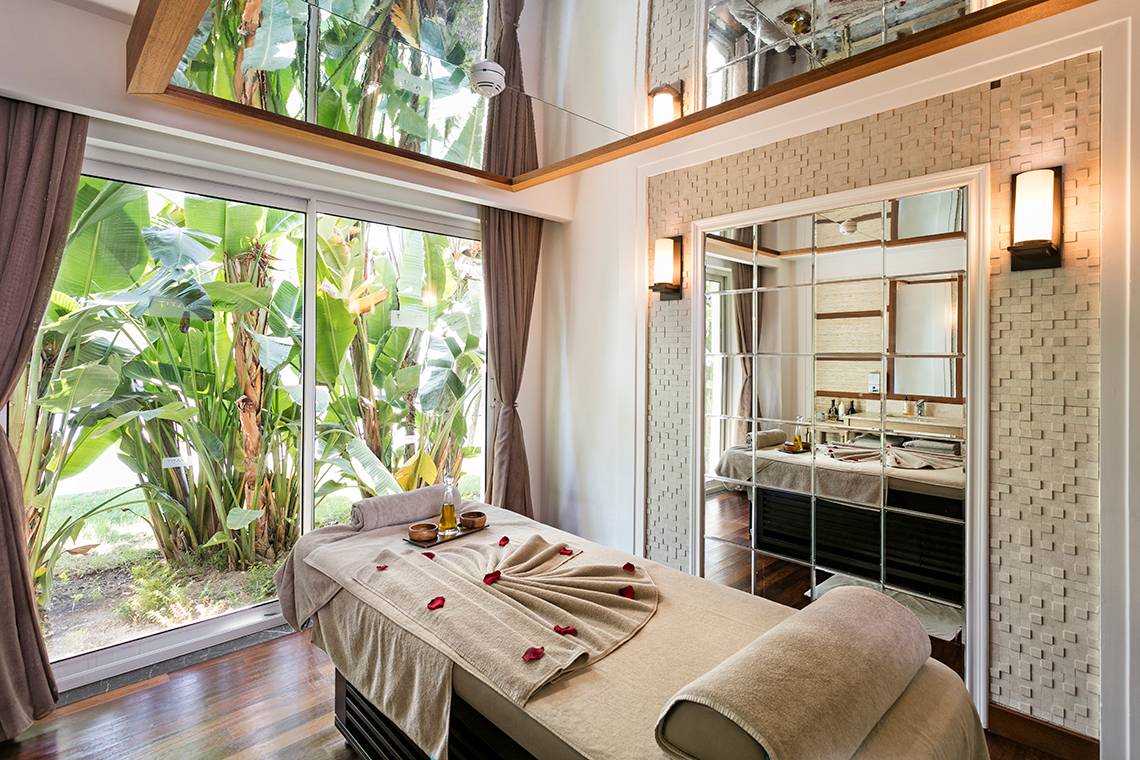 Massagebehandlung im Titanic Deluxe Golf Belek mit Blick auf Pflanzen und Spiegel.