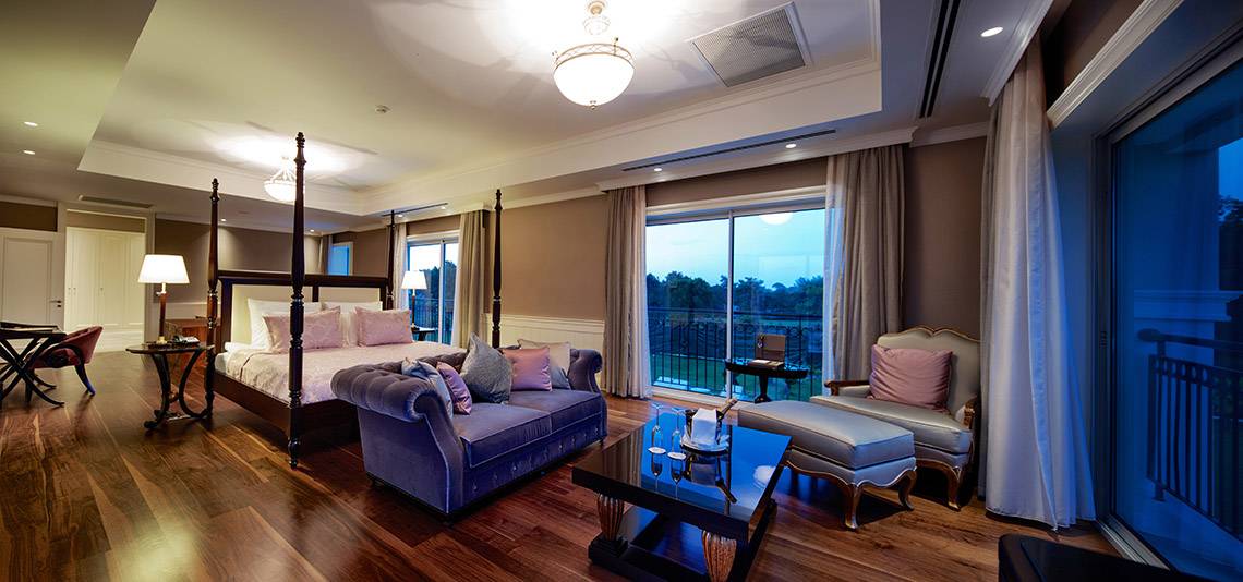 Luxuriöses Schlafzimmer im Titanic Deluxe Golf Belek mit großem Bett, Couch, Tisch und großem Fenster.