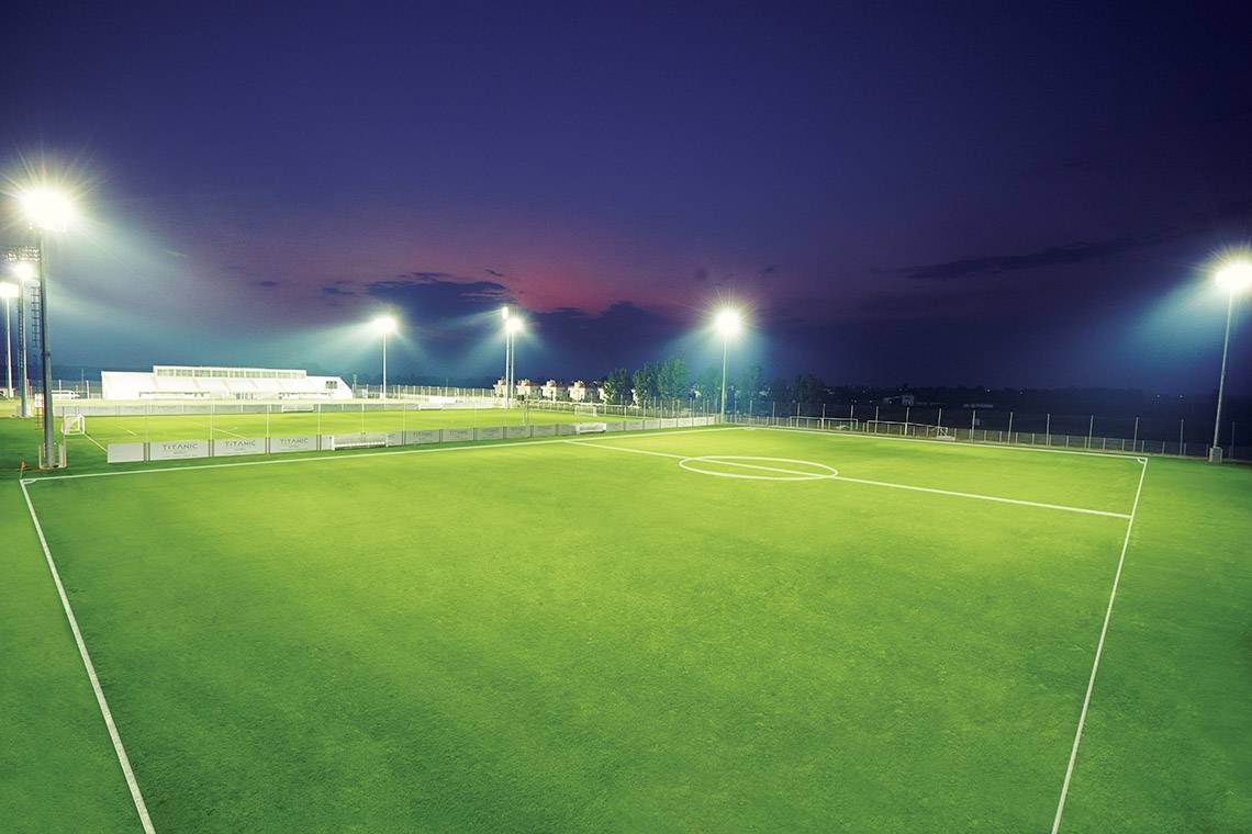 Fussballplatz bei Nacht mit Flutlichtern und leerem Spielfeld