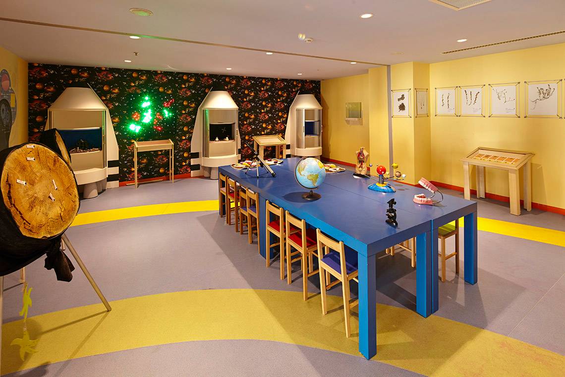 Innenbereich des Titanic Deluxe Golf Belek Hotels mit blauem Tisch und bunten Räumen.