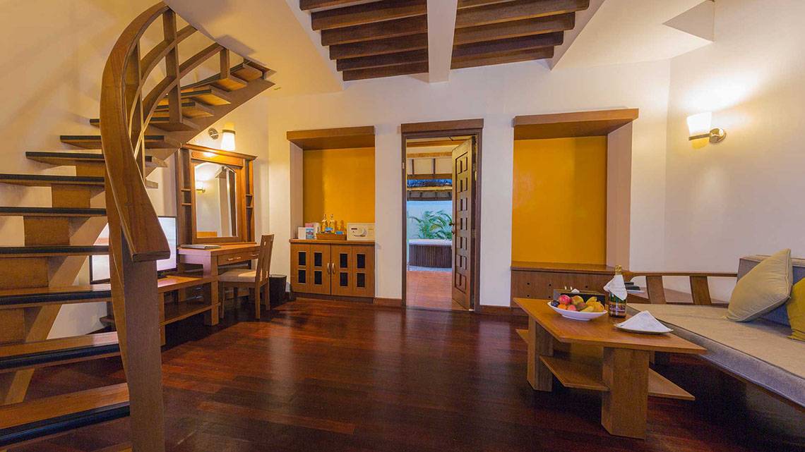 Inneneinrichtung eines Zimmers im Bandos Maldives Hotel mit hölzerner Treppe und Möbeln.