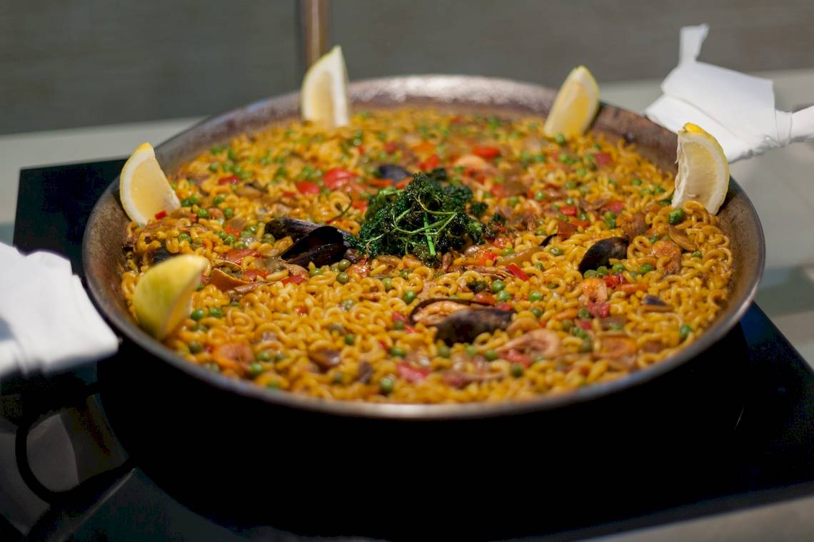 Ein großer Teller Paella mit Reis, Meeresfrüchten und Gemüse, serviert im Timor Hotel.