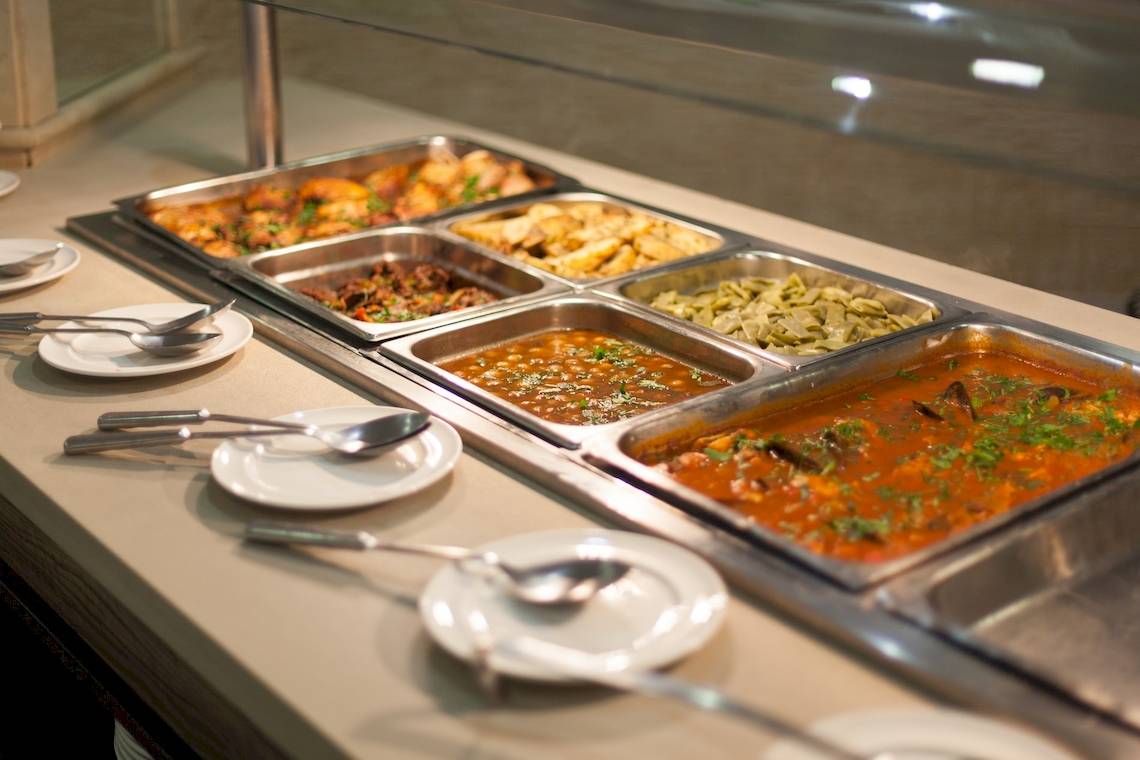 Buffet-Tisch im Timor Hotel mit verschiedenen Gerichten und Besteck.