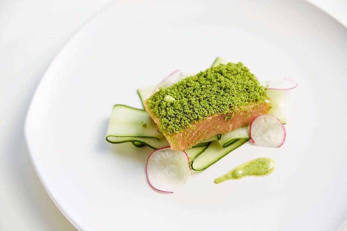 Ein Gericht mit Lachs auf Gurke, umgeben von Radieschen und sauereis.
