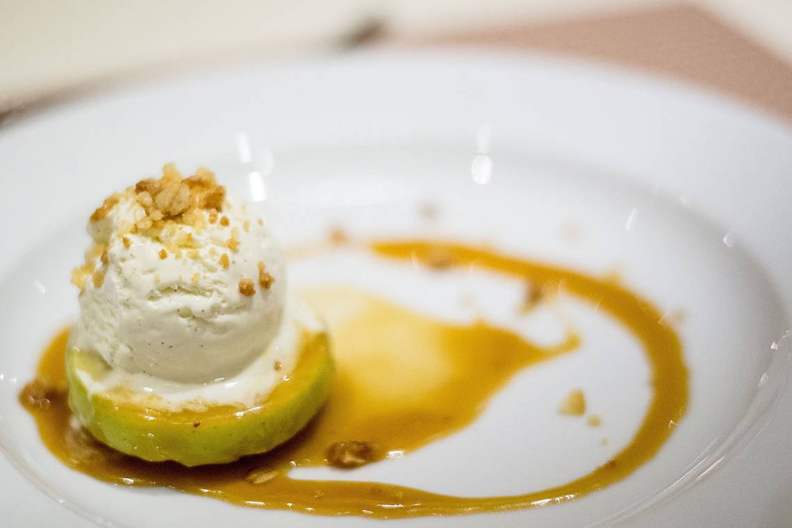Eisbedeckter Apfel auf einem weißen Teller mit Karamellsauce.