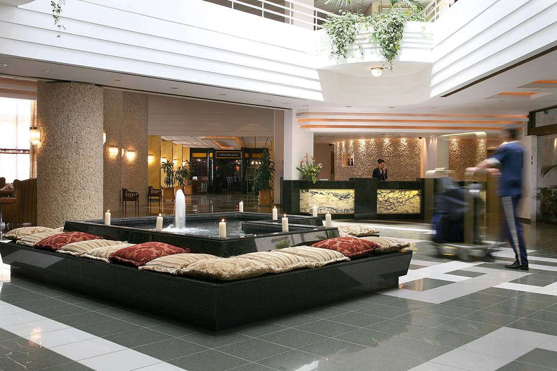Ansicht der Lobby des GrandResort Limassol Hotels mit Wasserbrunnen und Angestellten.