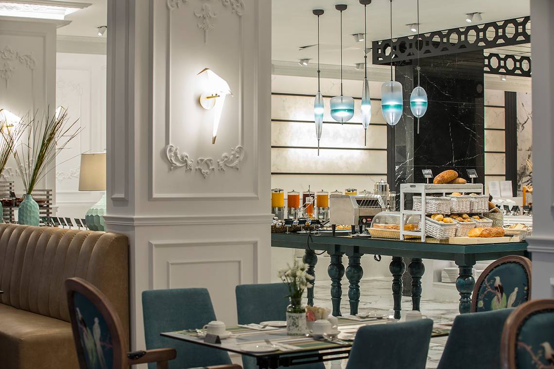Frühstücksbereich im GrandResort Limassol mit Tisch, Stühlen, Buffet und Dekoration.