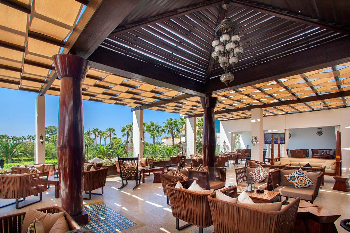 Loungebereich im GrandResort Limassol mit Holzmöbeln und Deckenlampen.