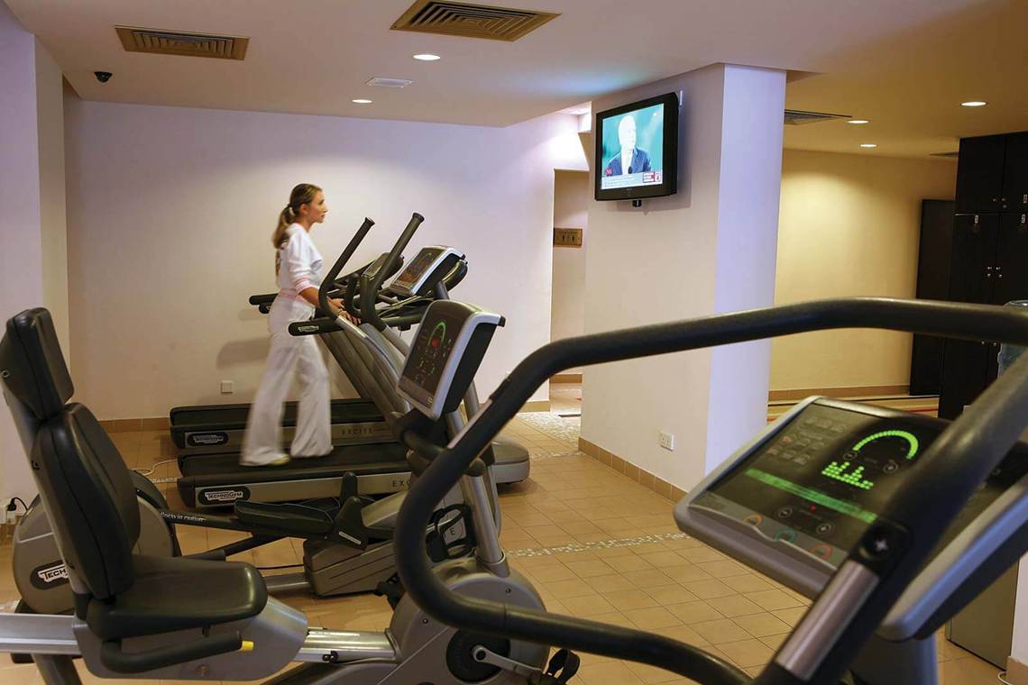 Frau im weißen Outfit läuft auf einem der drei Tretmühlen im Fitnessstudio des GrandResort Limassol.
