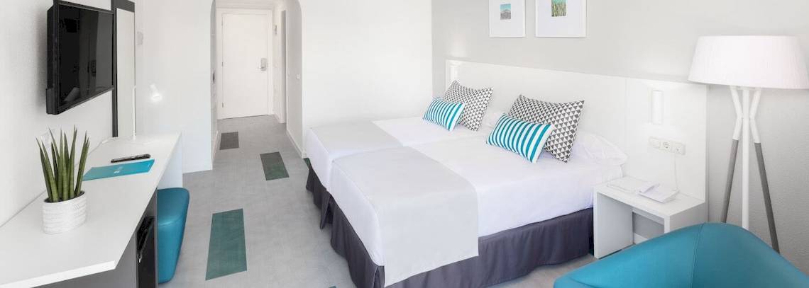 Hotelzimmer im Bluesea Interpalace mit zwei Betten, Fernseher, Schreibtisch und moderner Einrichtung.