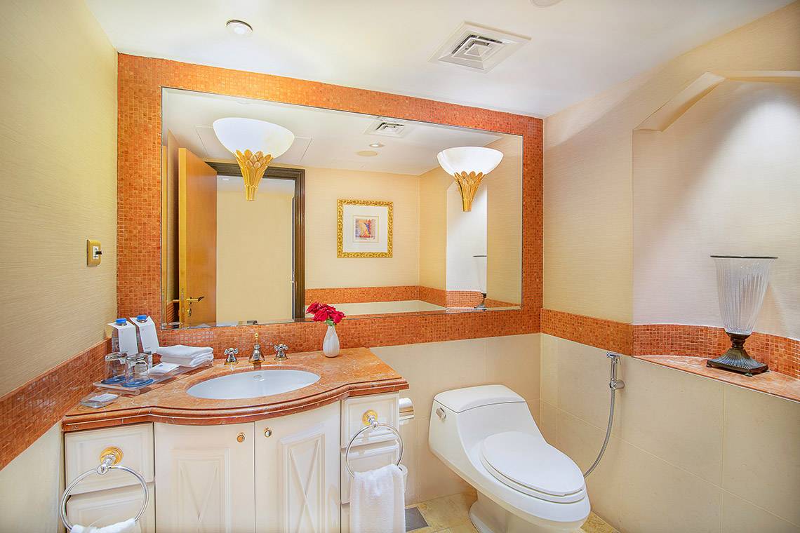 Badezimmer im Sheraton Abu Dhabi Hotel mit Spiegel, Waschbecken, Toilette und Dekoration.