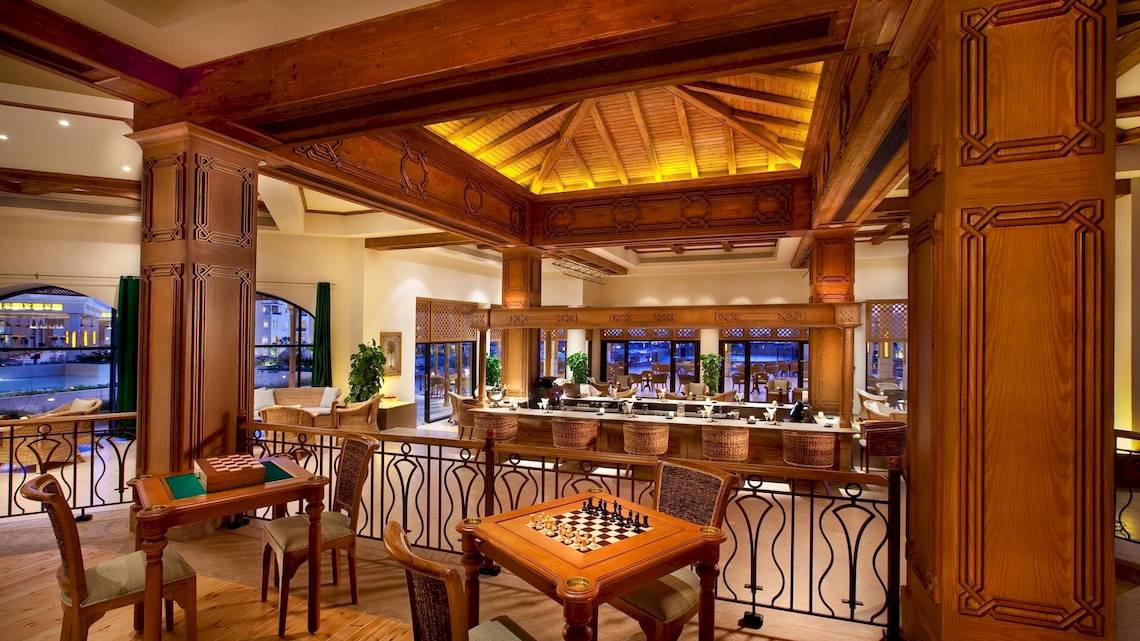 Lobby-Lounge des Kempinski Hotels Soma Bay mit Holzmöbeln und einem Schachspieltisch.