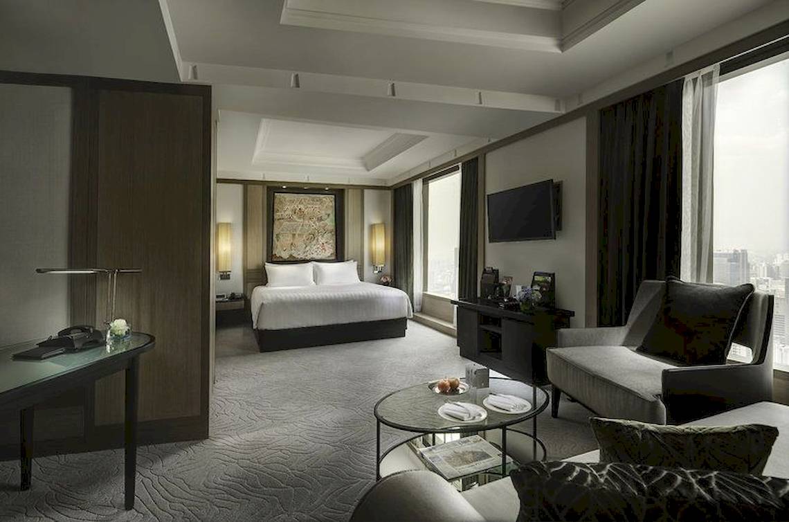 Hotelzimmer im Banyan Tree Bangkok mit einem großen Bett, Schreibtisch, Fernseher und Wohnzimmermöbeln.