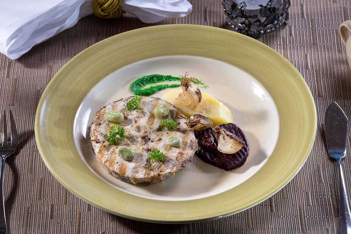 Gegrillter Fisch auf einem Teller im Cactus Royal Hotel, mit Kartoffeln und Gemüse.