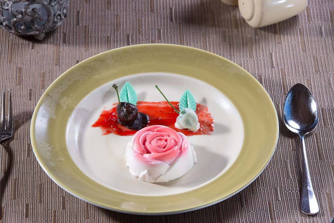 Rosa Praline auf Teller im Hotel Cactus Royal mit Früchten und Blattdekor.