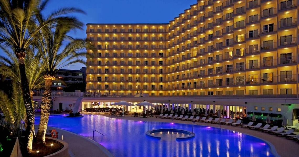 Das Sol Guadalupe Hotel bei Nacht mit beleuchteten Fenstern und einem großen Pool.