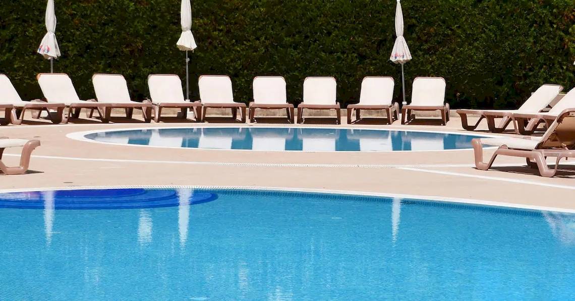 Schwimmbeckenbereich des Sol Guadalupe Hotels mit weißen Liegestühlen und Sonnenschirmen.