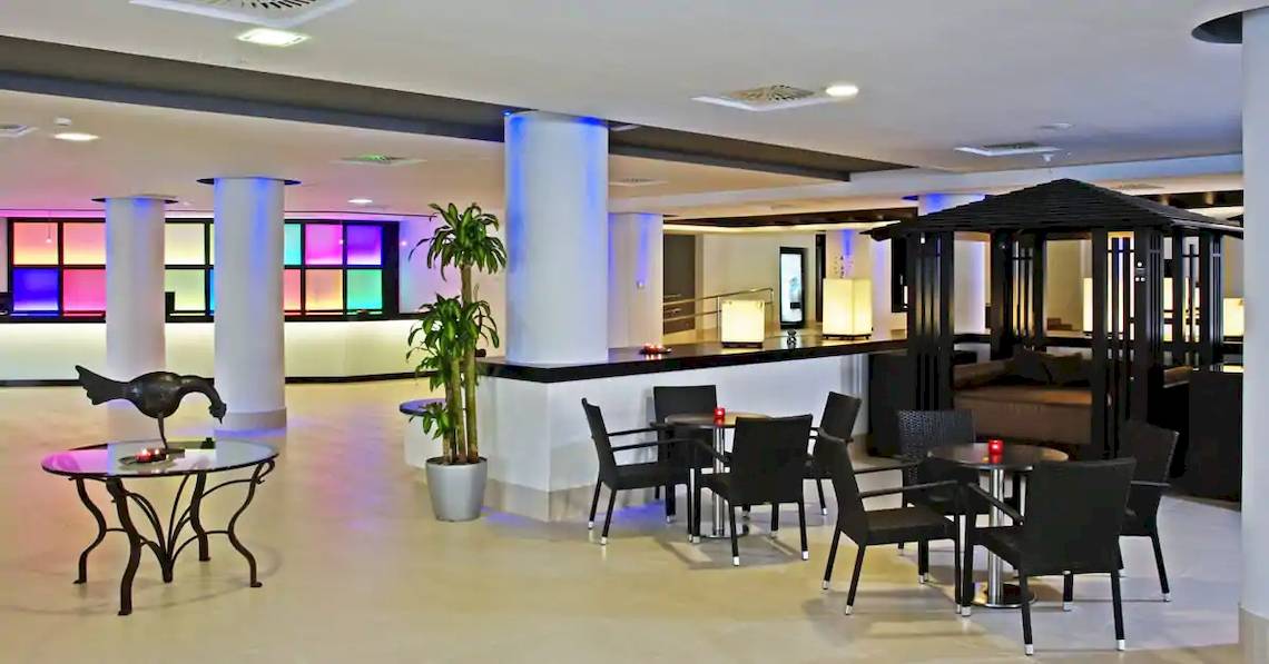 Lobby des Sol Guadalupe Hotels mit bunten Säulen und modernen Möbeln.