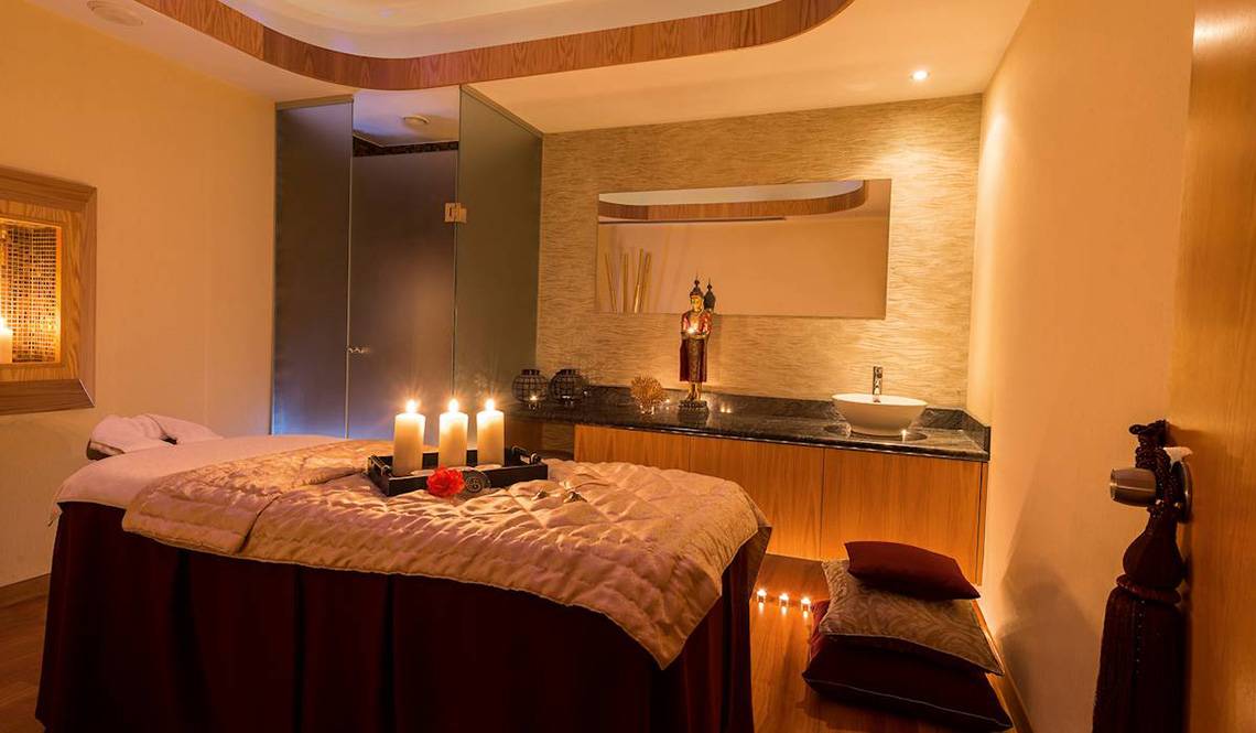 Spa-Behandlungsraum im Constantinou Bros Athena Royal Beach Hotel mit Kerzen und einem Bett.
